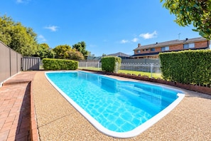 A rectangular swimming pool with a pebble-lined edge, surrounded by a brick patio. - Cosy Sunlit home with a Pool (Smithfield)