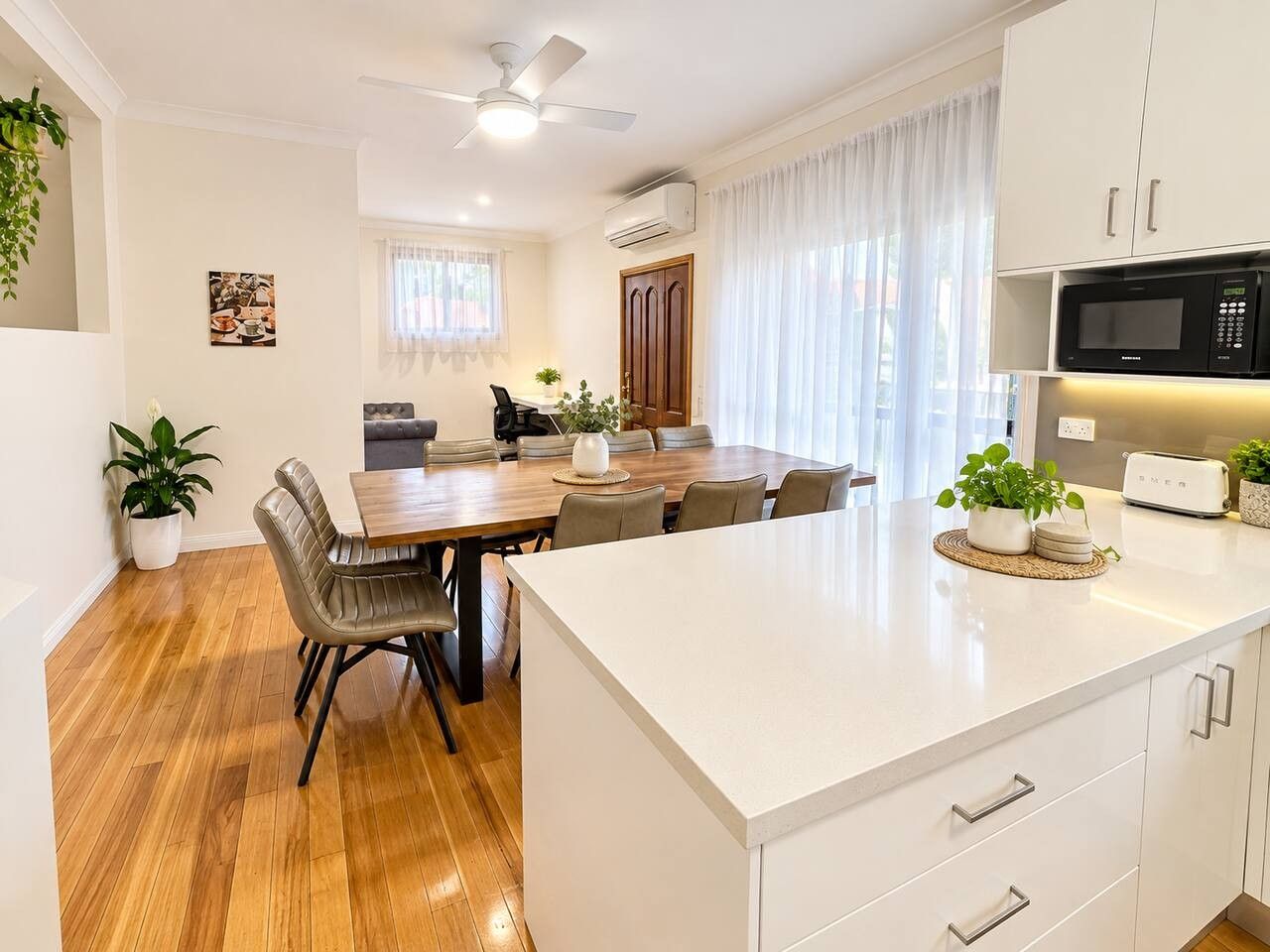 A modern kitchen with a dining area, white cabinetry, and a built-in microwave.