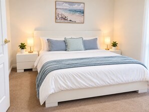 Un dormitorio con una cama, mesitas de noche, lámparas y un cuadro en la pared.