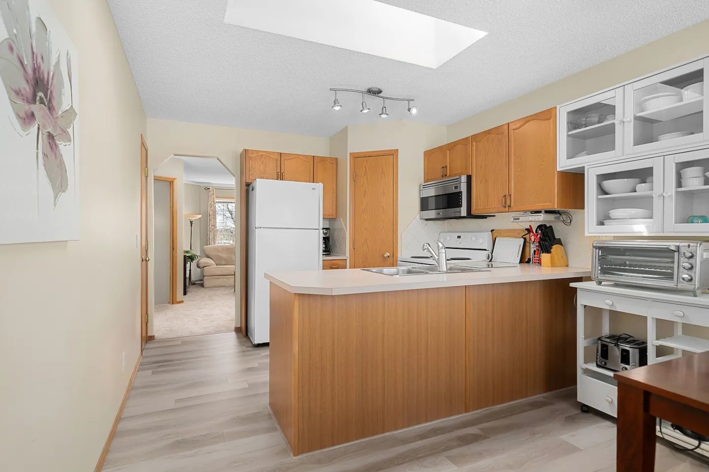 A modern kitchen with wooden cabinets, a built-in microwave, and a toaster.
