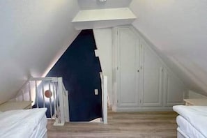 A room with a sloped ceiling, a staircase leading to an upper level, and a door. - Ameland Reethus (Wenningstedt) (Wenningstedt-Braderup)