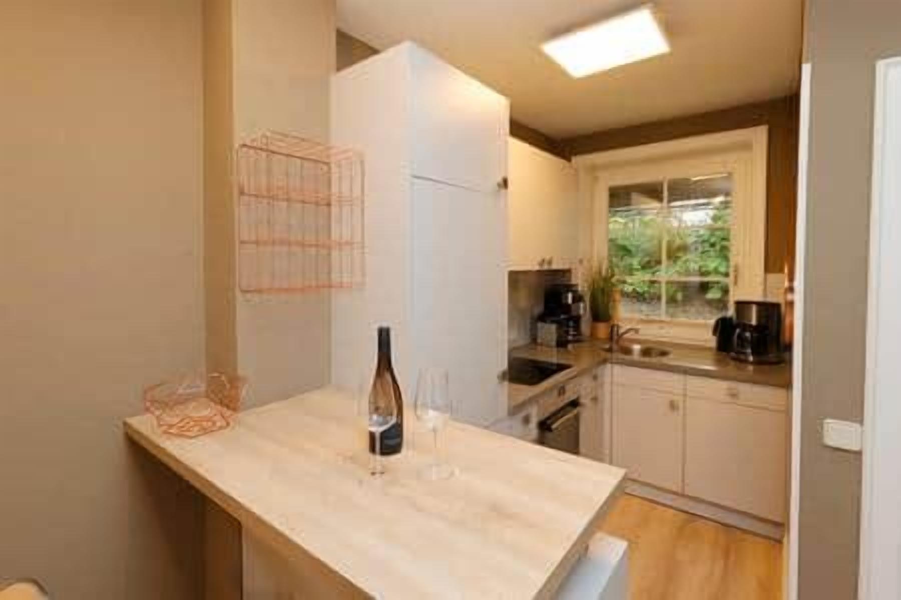 Una cocina con mostrador, una botella de vino y una copa de vino.