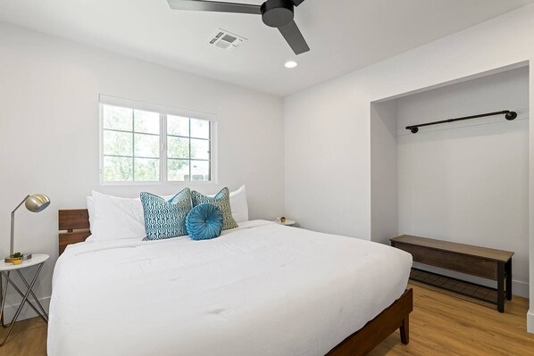 A bedroom with a bed, a bedside table, a lamp, a window, and a ceiling fan. - The Elliott at Biltmore | Fire Pit, Grill (Phoenix)