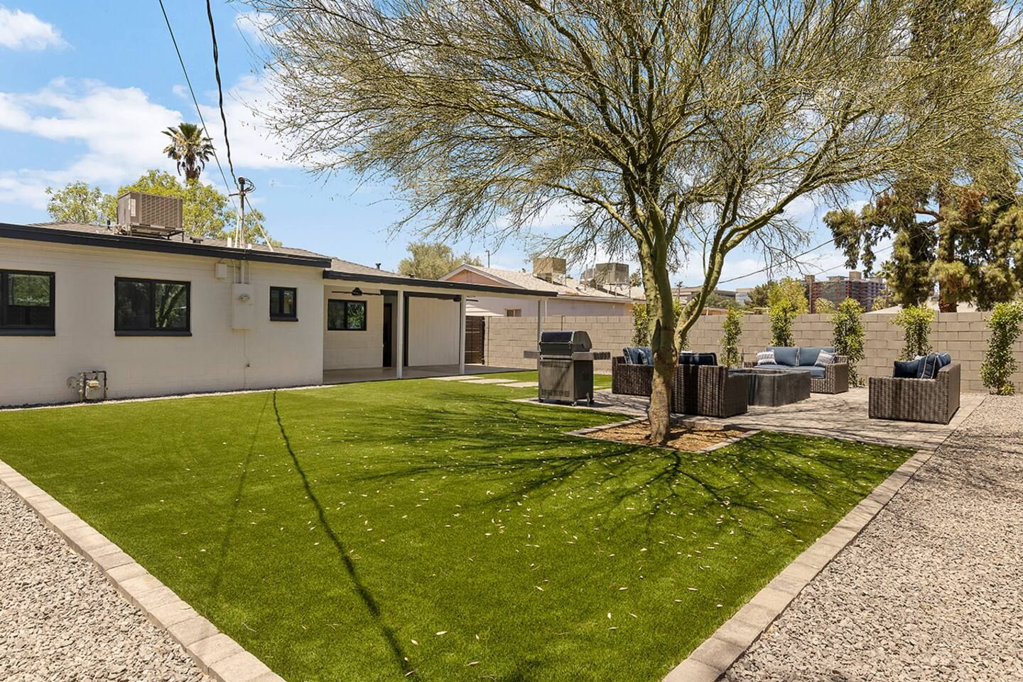 A residential property with a well-maintained lawn, outdoor seating area, and a garage.