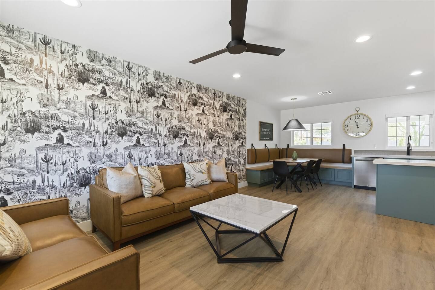 A modern living room with a brown sofa, a coffee table, and a kitchen area with a dining table and chairs.