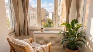 A cozy room with a view of buildings, a radiator, a chair, a table, a mug, and a potted plant. - 3-Storey Private Townhouse with Sauna,Bar,Terrace, 3BR,3BA (Beyoğlu)