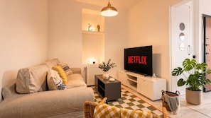 A living room with a sofa, a television displaying 'NETFLIX,' a potted plant, and a checkered floor. - 3-Storey Private Townhouse with Sauna,Bar,Terrace, 3BR,3BA (Beyoğlu)