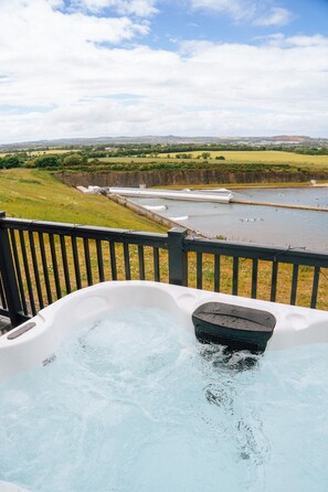 A hot tub with a view of a river and fields. - Lost Shore Surf Resort - 4 Bed Lodge With Hot Tub (Newbridge)