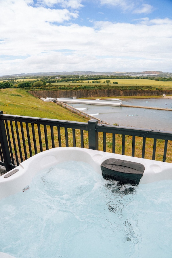 Un jacuzzi con vista a un río y campos.