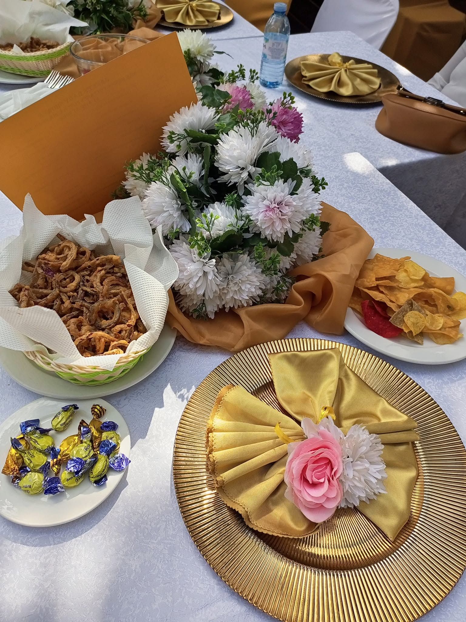 A table set with plates of food, a bouquet of flowers, and a decorative fan.