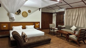 Una habitación de hotel con cama, sofá, sillón, mesa de centro y armario.