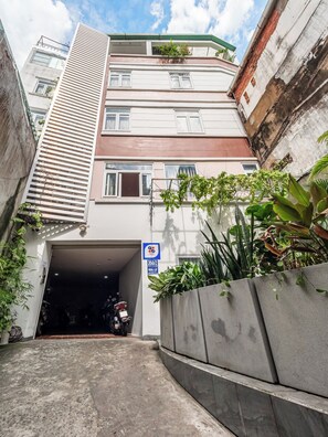 Um corredor estreito que leva à entrada de um edifício, com sinalização indicando área de estacionamento.