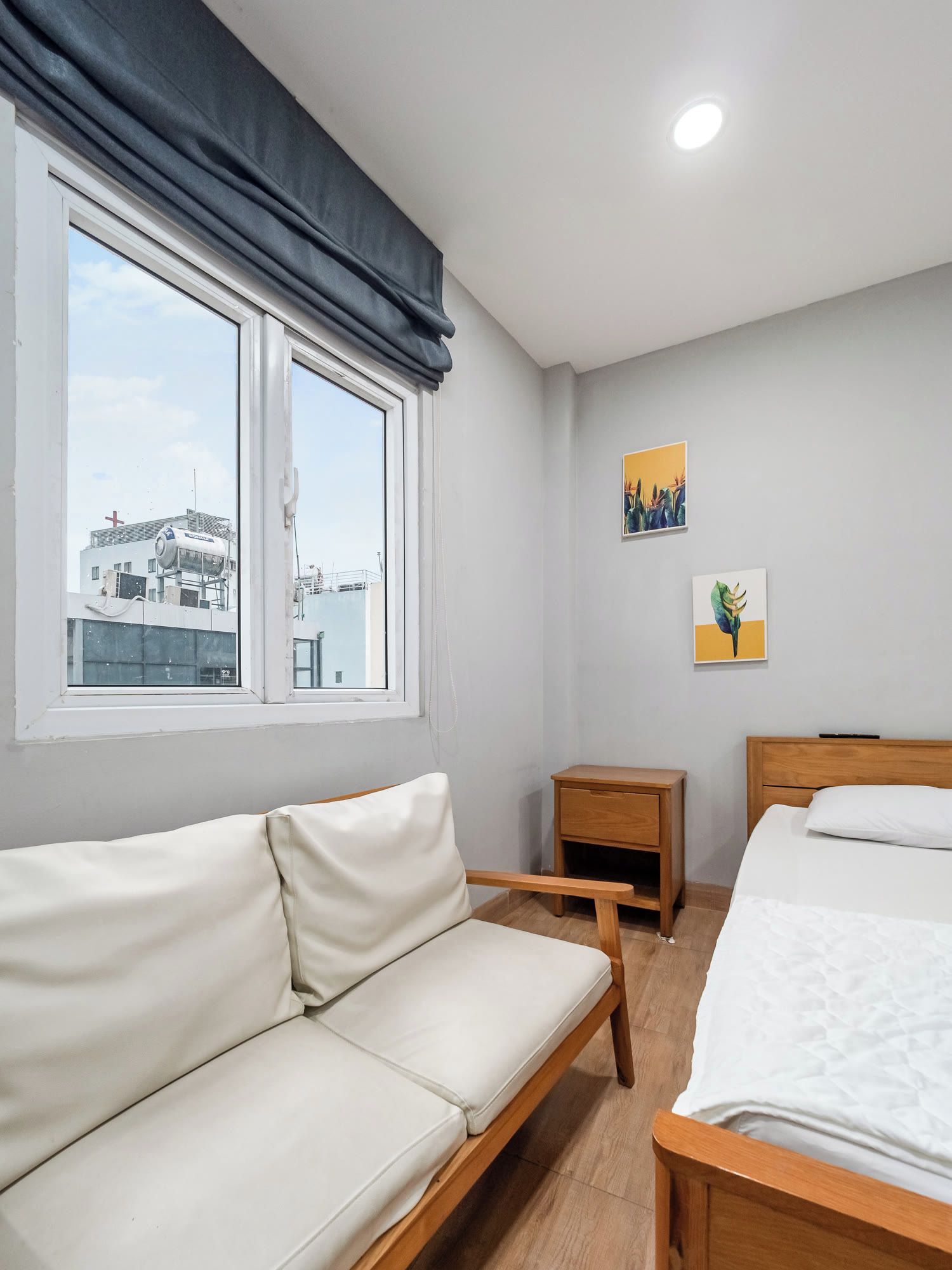 Een hotelkamer met een bank, een bed, een nachtkastje en twee kunstwerken aan de muur.