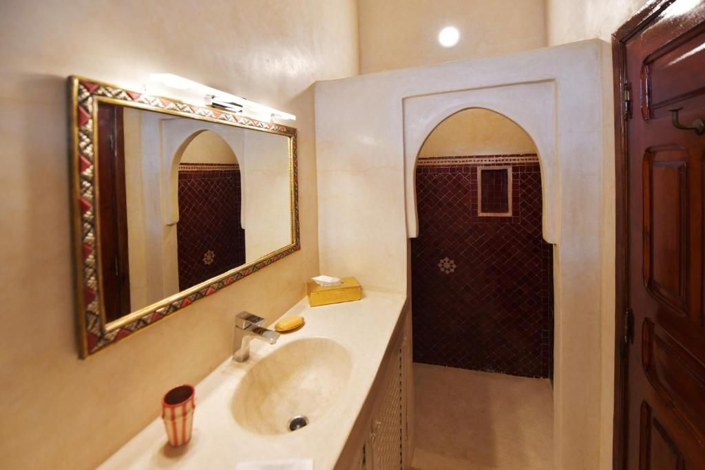 A bathroom with a large mirror, a sink, and a door leading to another room.