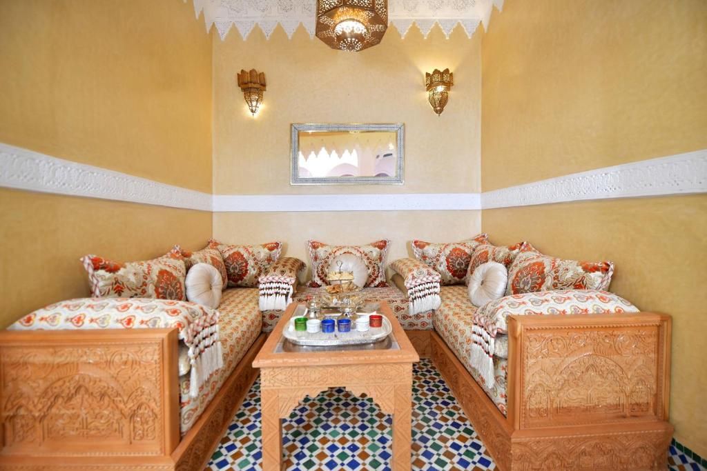 A traditional Moroccan room with a sofa set, a tray table, and patterned floor tiles.