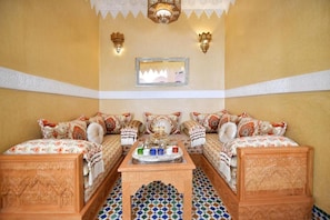 A traditional Moroccan room with a sofa set, a tray table, and patterned floor tiles. - Riad DAR ORIANE & SPA (Marrakech)