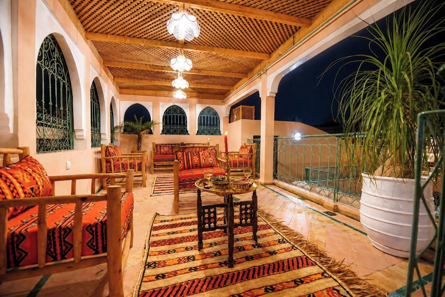 An outdoor seating area with wooden furniture and patterned rugs.