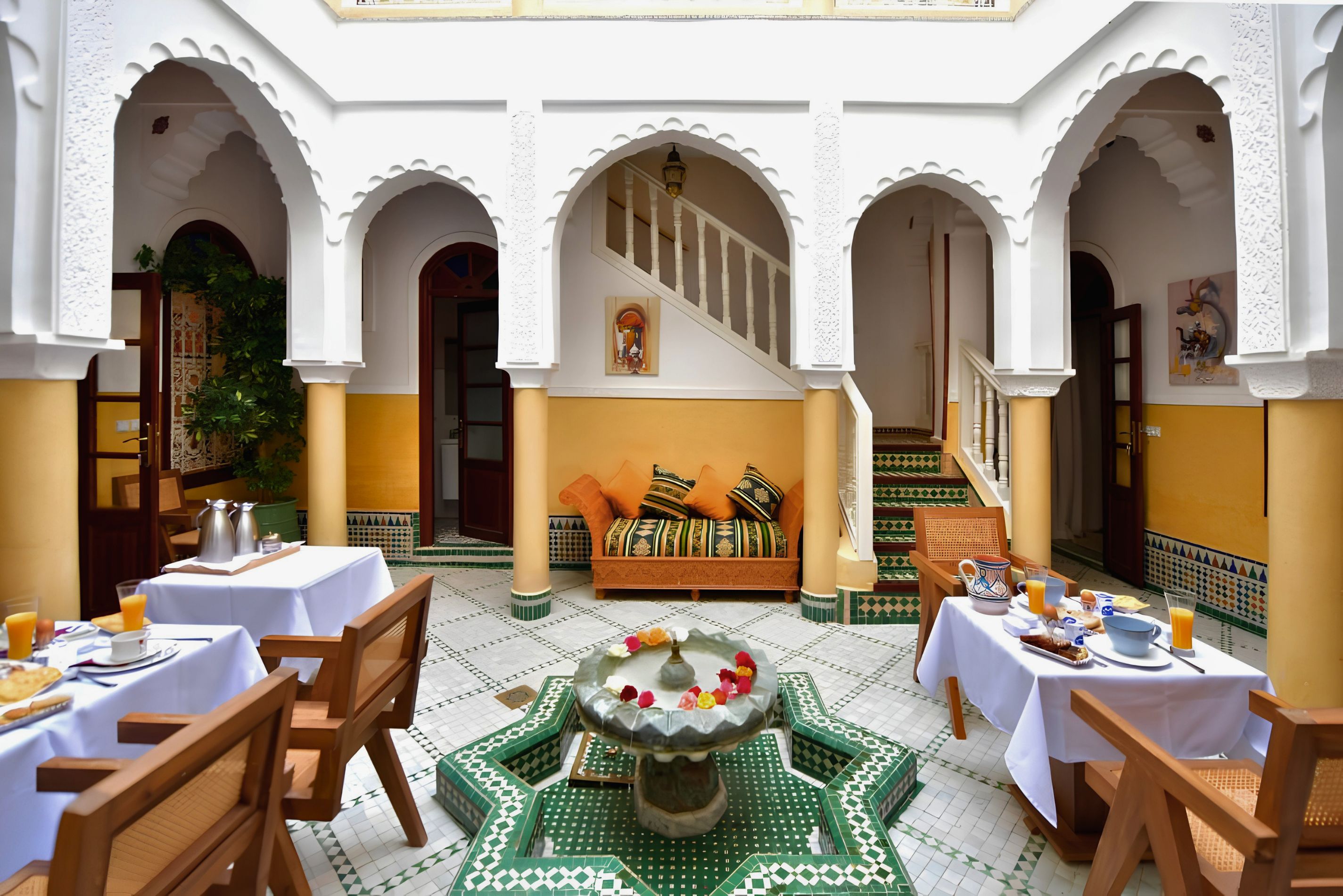 Un patio con zona de comedor, un sofá y una escalera.