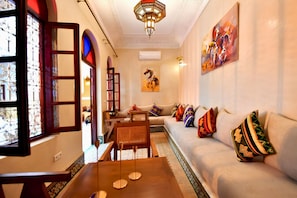 A living room with a sofa, a coffee table, and a painting on the wall. - Riad DAR ORIANE & SPA (Marrakech)
