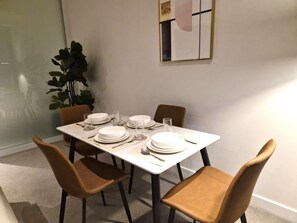 Une table à manger dressée avec des assiettes, des verres et des couverts, entourée de chaises.