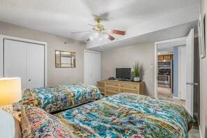 A bedroom with two beds, a ceiling fan, a television, and a dresser. - 3BR Beachfront condo w/ Gulf views, pools, hot tub and direct beach access (Orange Beach)