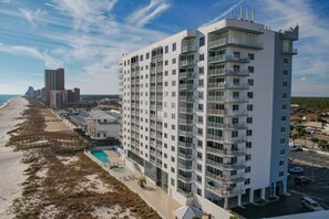 A high-rise hotel with multiple balconies, a pool, and a beach view. - 3BR Beachfront condo w/ Gulf views, pools, hot tub and direct beach access (Orange Beach)