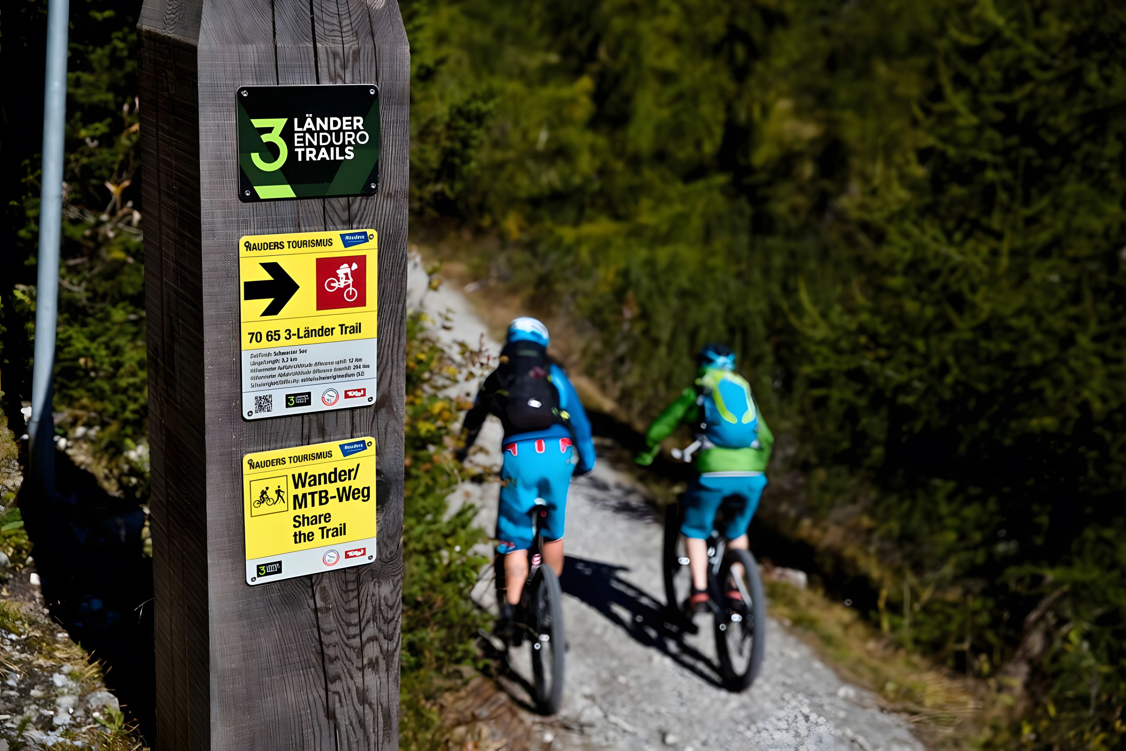 Um poste de madeira com várias placas, incluindo uma para as 3 Trilhas Lander e outra para Wander/MTB-Weg.