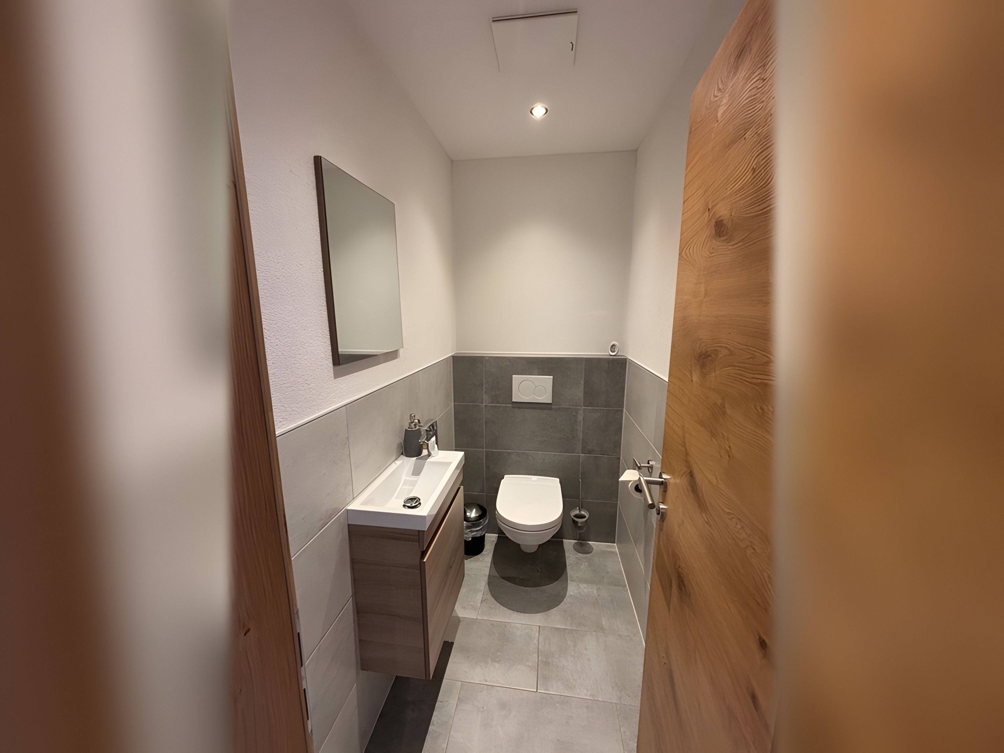 A modern bathroom with a toilet, sink, and mirror.