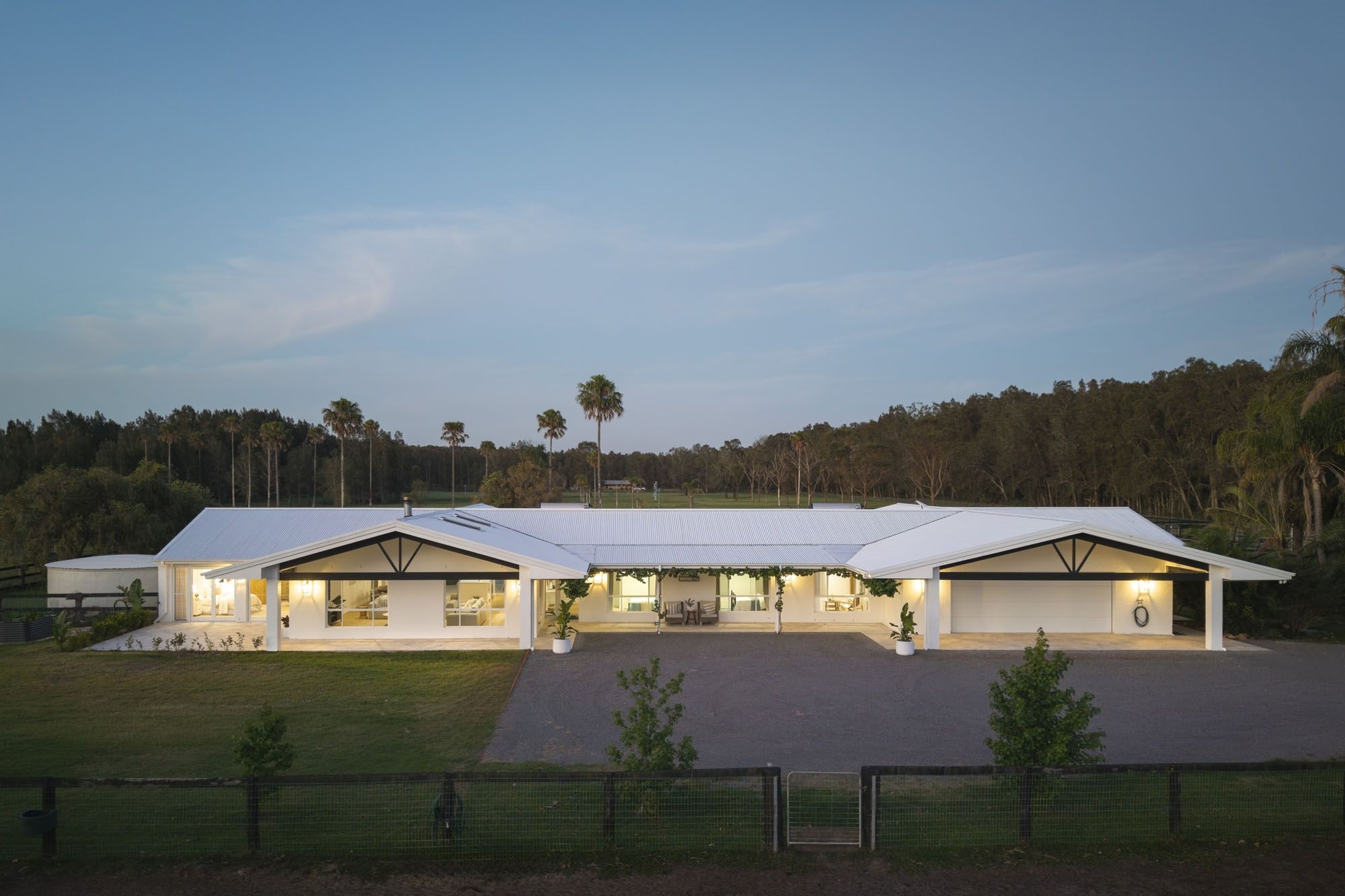 A modern building with a flat roof, large windows, and a covered outdoor area.