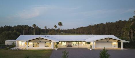 A modern building with a flat roof, large windows, and a covered outdoor area.