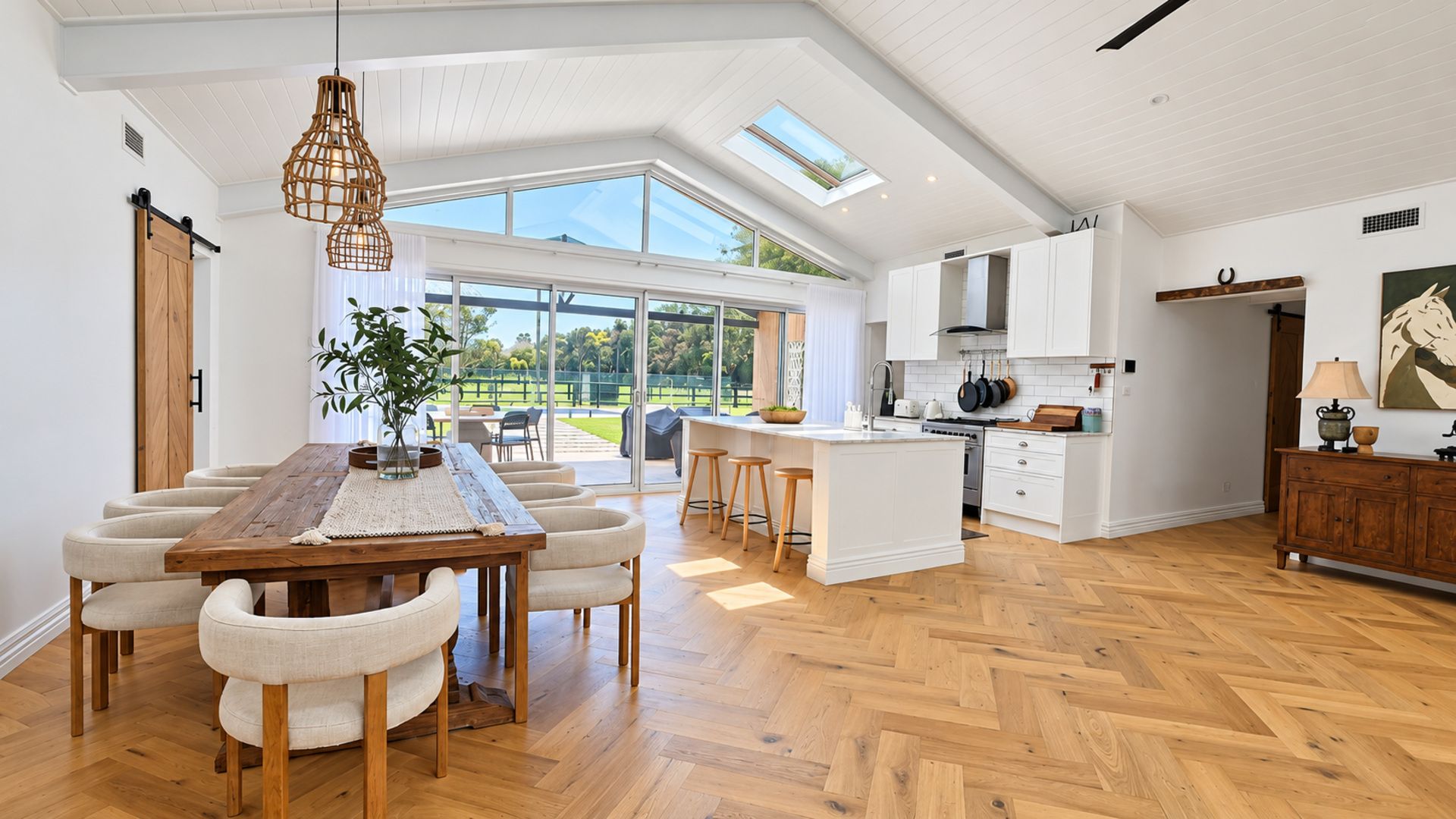 A spacious kitchen with a central island, large windows, and a herringbone wood floor.