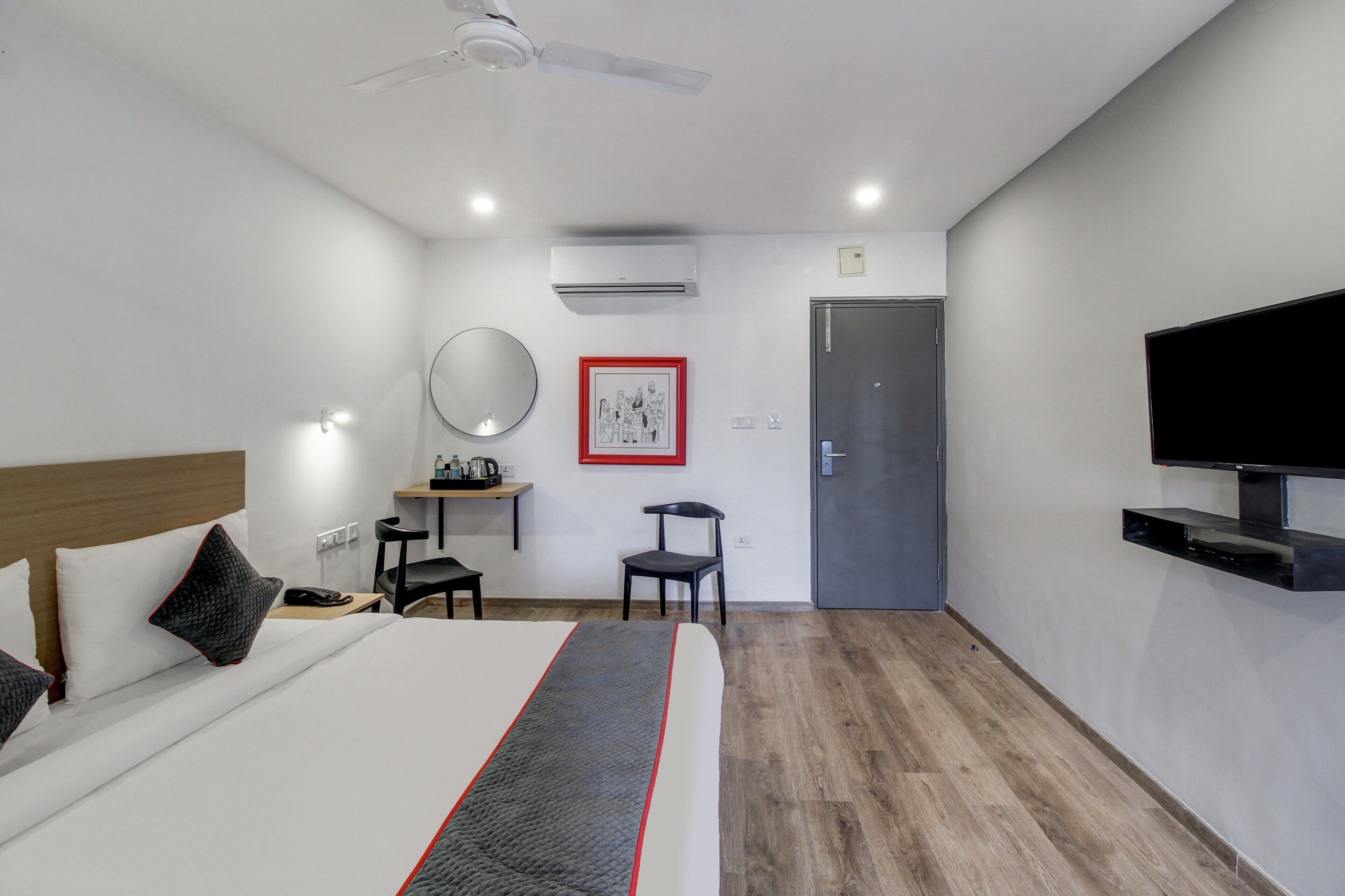 A hotel room with a bed, a desk, a chair, a television, and a door.