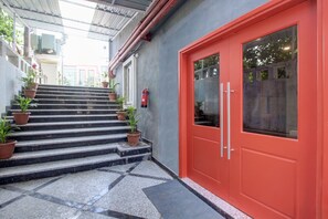 Una escalera con plantas en macetas que lleva a una puerta roja con paneles de vidrio.