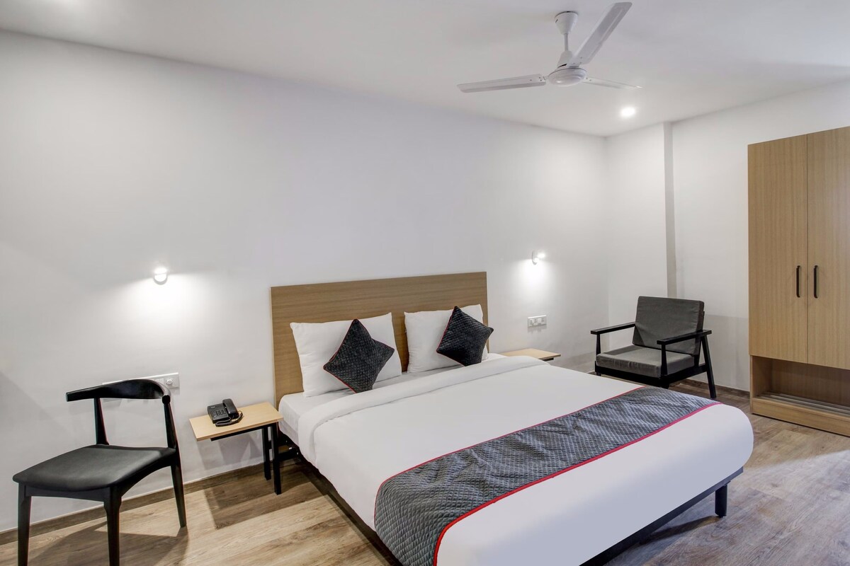 Una habitación de hotel con una cama, un escritorio, una silla, un armario y un ventilador de techo.