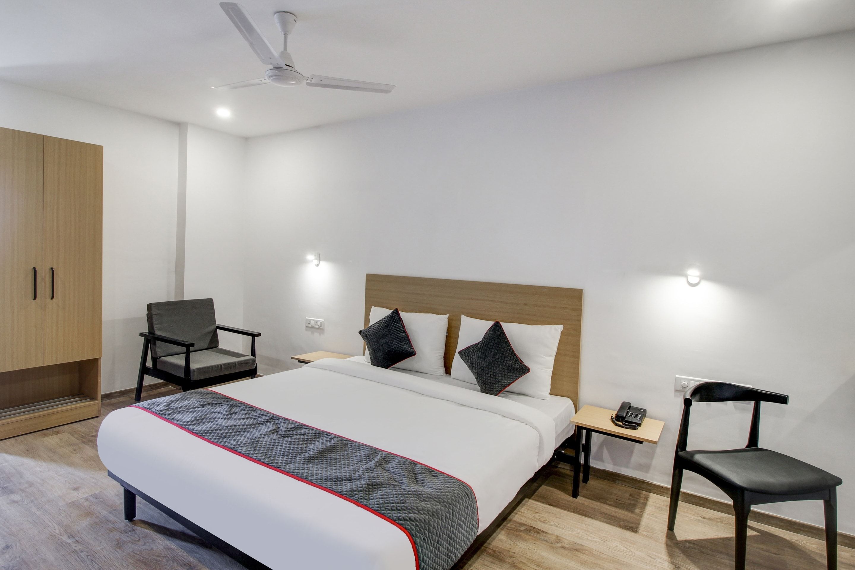 Una habitación de hotel con cama, una silla, un escritorio y un armario.
