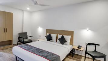 Una habitación de hotel con cama, una silla, un escritorio y un armario.