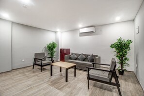A modern living room with a sofa, two armchairs, a coffee table, and two potted plants.