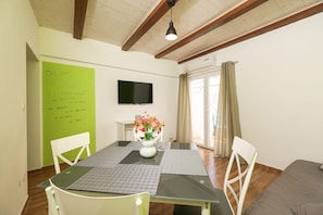 A dining area with a table, chairs, a flat-screen TV, and a green wall with motivational text. - Villa Feliks ZadarVillas (Ljubac)