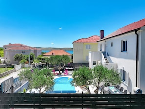 A residential area with a swimming pool, a white building with a red roof, and a view of the sea. - Villa Feliks ZadarVillas (Ljubac)