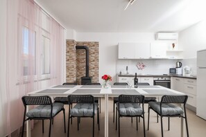 Une cuisine moderne avec des meubles blancs, une cuisinière encastrée et un coin repas comprenant une table et des chaises.