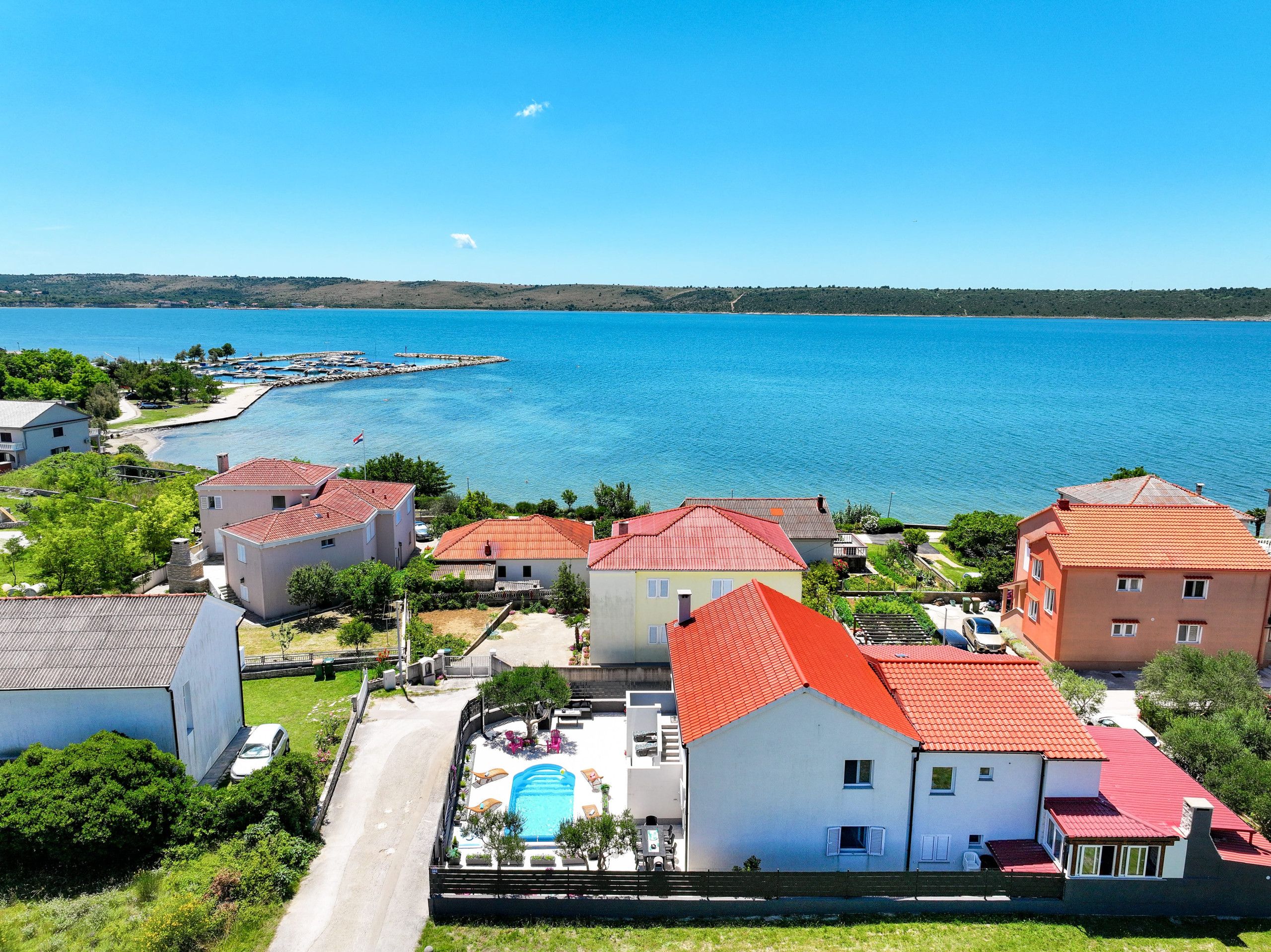 Un quartier résidentiel situé sur la côte, avec des maisons, une piscine et une vue dégagée sur la mer.
