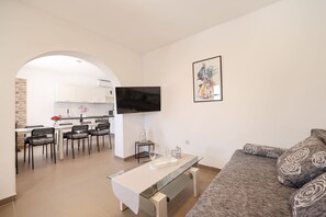 A modern living room with a sofa, a TV mounted on the wall, and a dining area with chairs and a table. - Villa Feliks ZadarVillas (Ljubac)