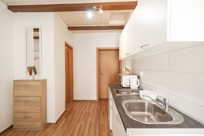 A modern kitchen with wooden cabinets, a stainless steel sink, and a microwave. - Villa Feliks ZadarVillas (Ljubac)
