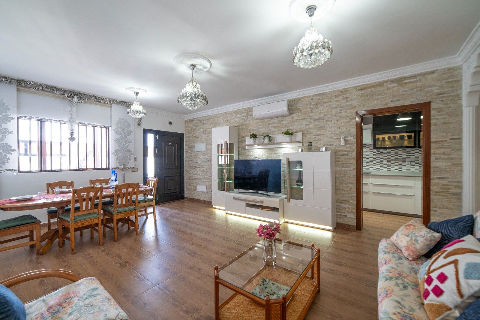 A modern living room with a dining area, a kitchen, and a TV.