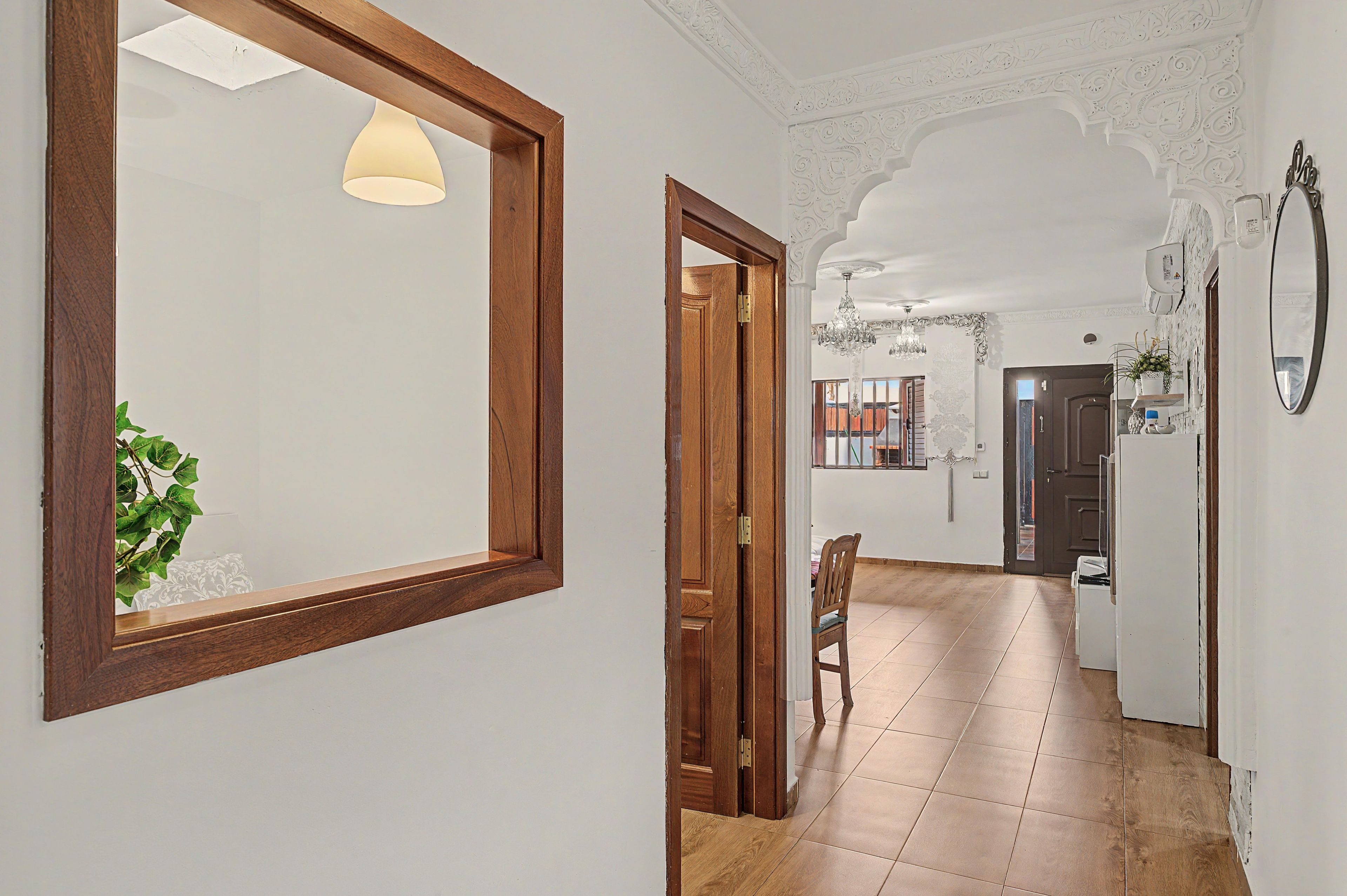 A hallway with a wooden door, a chair, and a potted plant.