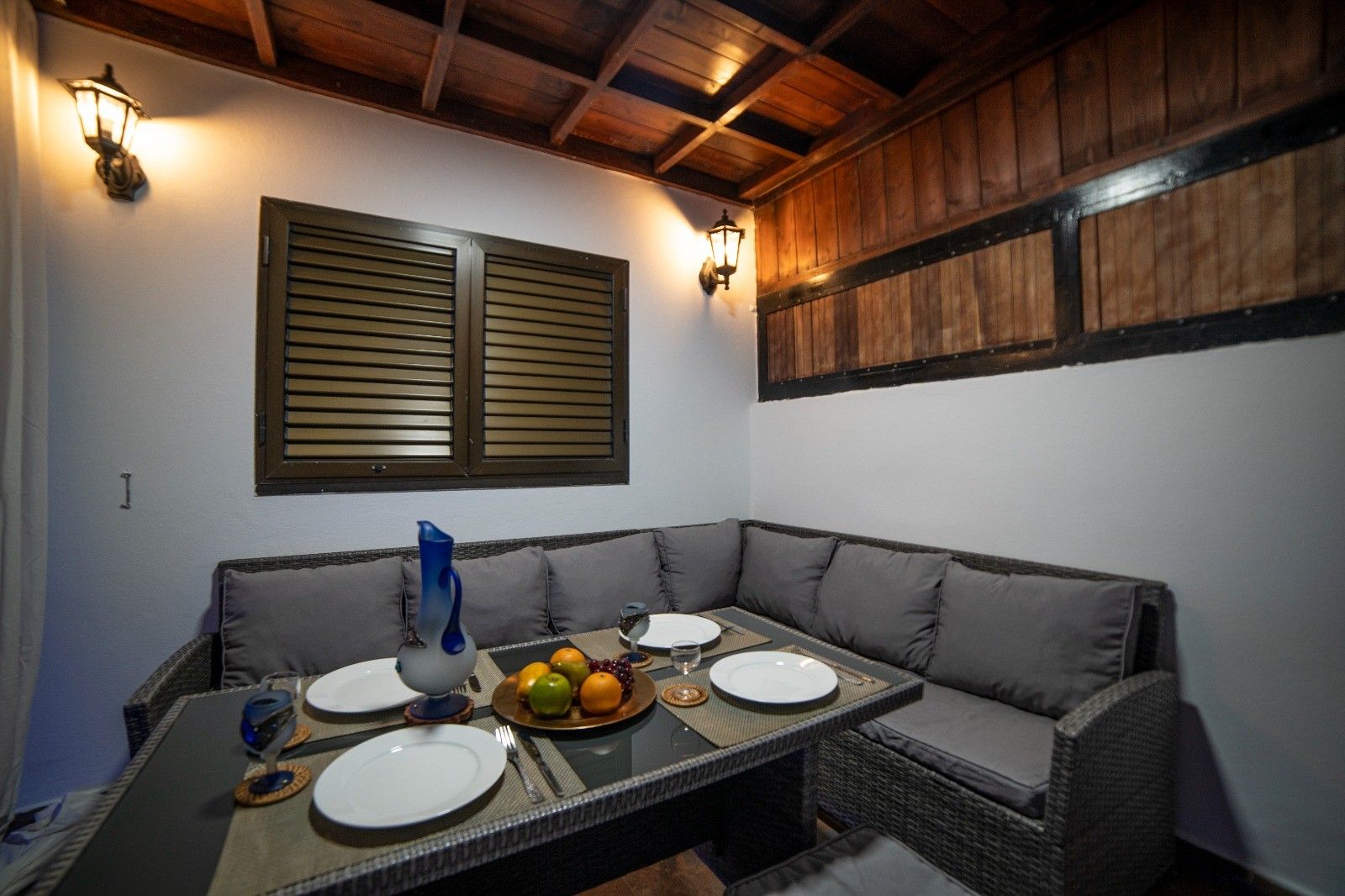 Un comedor con una mesa larga, asientos acolchados y luminarias fijadas a la pared.