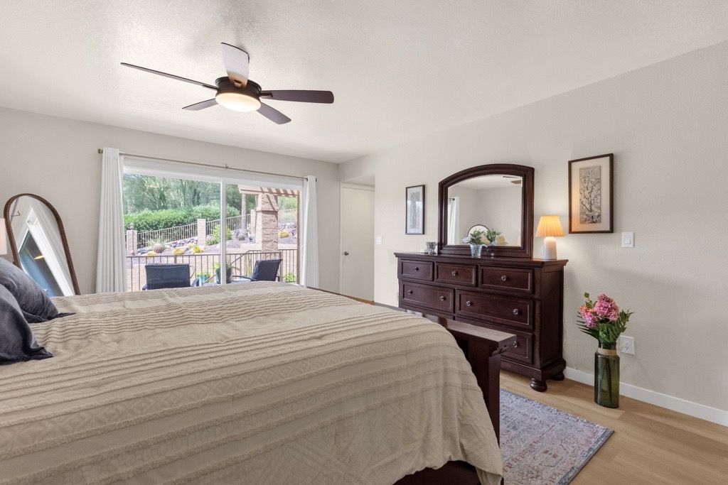 Un dormitorio con cama, cómoda, espejo y vistas al exterior.