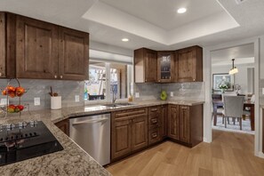 A modern kitchen with wooden cabinets, a stainless steel dishwasher, and a granite countertop.