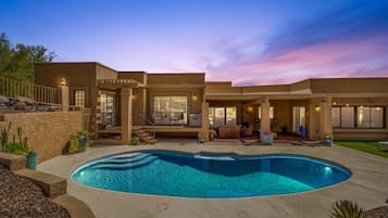 A residential property with a swimming pool, outdoor seating, and a landscaped garden.