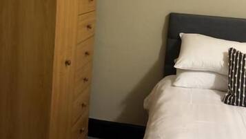 Un dormitorio con una cama, un aparador de madera y una pequeña planta en maceta.